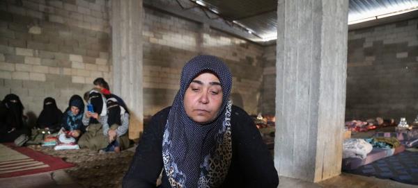A woman sits in a shelter for displaced people after fleeing her home in northern Syria.